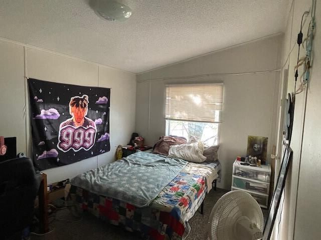 bedroom with a textured ceiling and lofted ceiling