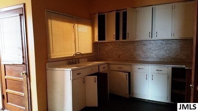 kitchen with decorative backsplash, sink, and white cabinetry