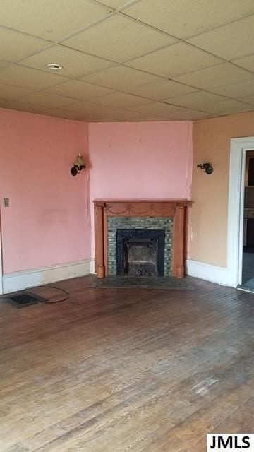 unfurnished living room with a tiled fireplace, hardwood / wood-style flooring, and a paneled ceiling