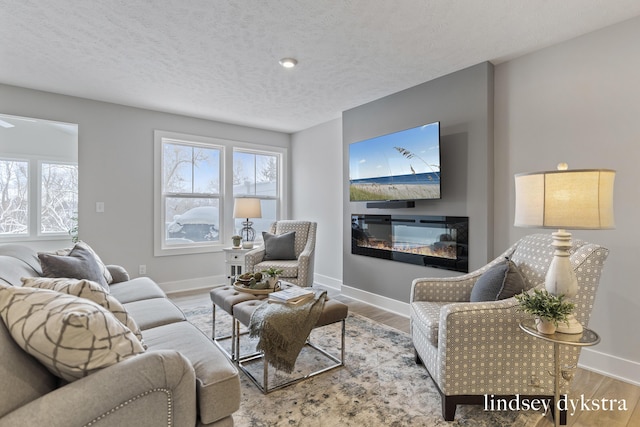 living room with plenty of natural light, wood finished floors, baseboards, and a textured ceiling