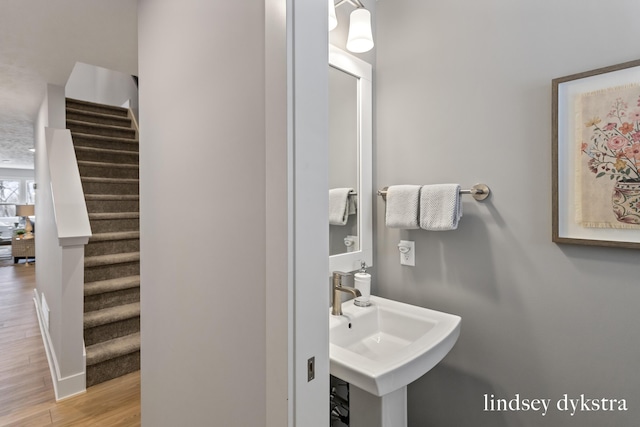 bathroom featuring wood finished floors, baseboards, and a sink