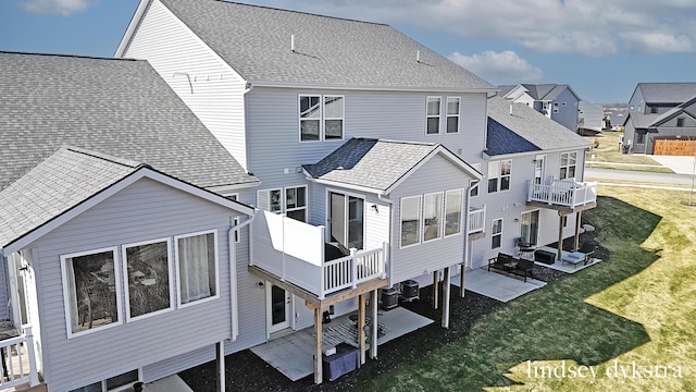 back of property with a residential view, a patio, a lawn, and roof with shingles