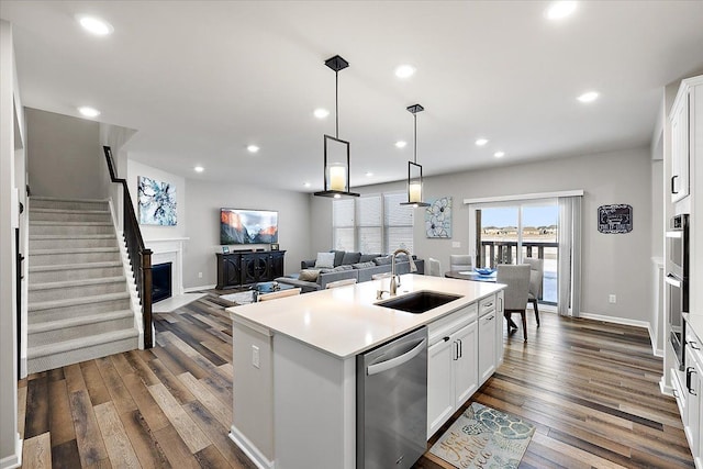 kitchen featuring an island with sink, white cabinetry, sink, hanging light fixtures, and stainless steel appliances