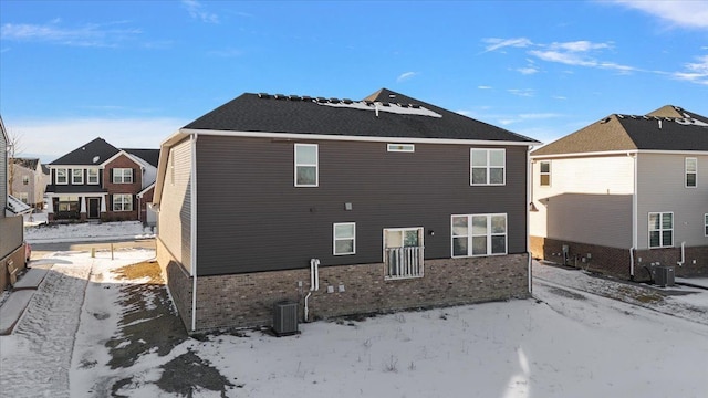 snow covered house featuring central AC unit