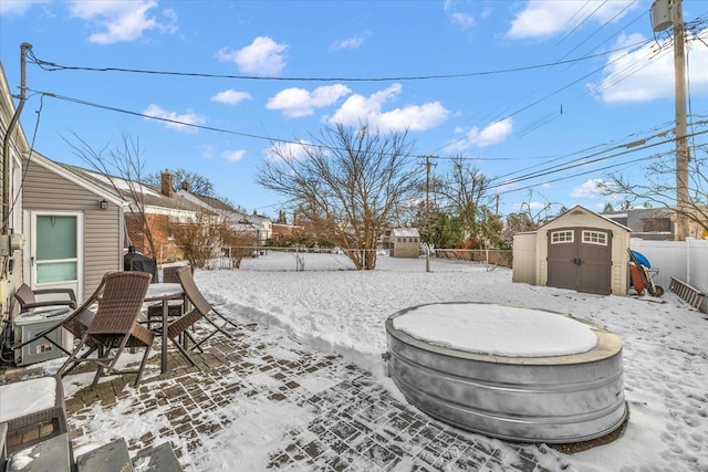 snowy yard featuring a storage shed