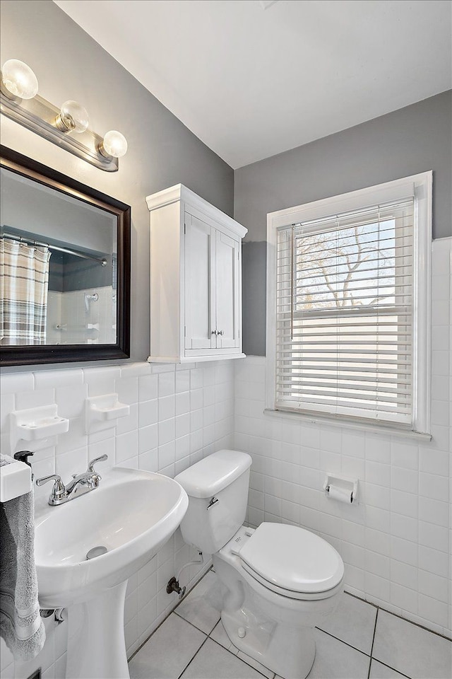 bathroom with sink, toilet, tile patterned floors, and tile walls