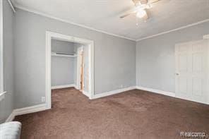 unfurnished bedroom with a closet, ceiling fan, ornamental molding, and dark colored carpet