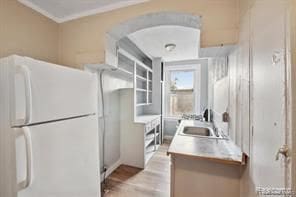 kitchen featuring sink, crown molding, and white fridge