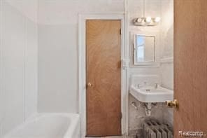 bathroom with sink, radiator, and a bathing tub