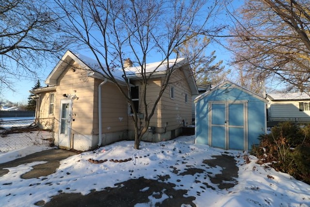 snow covered house featuring a storage unit