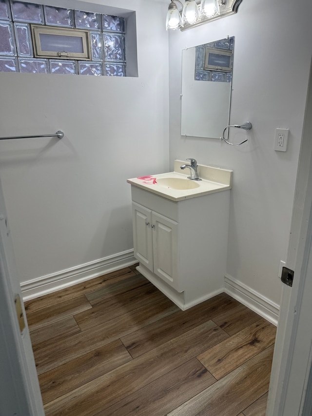 bathroom with baseboards, wood finished floors, and vanity