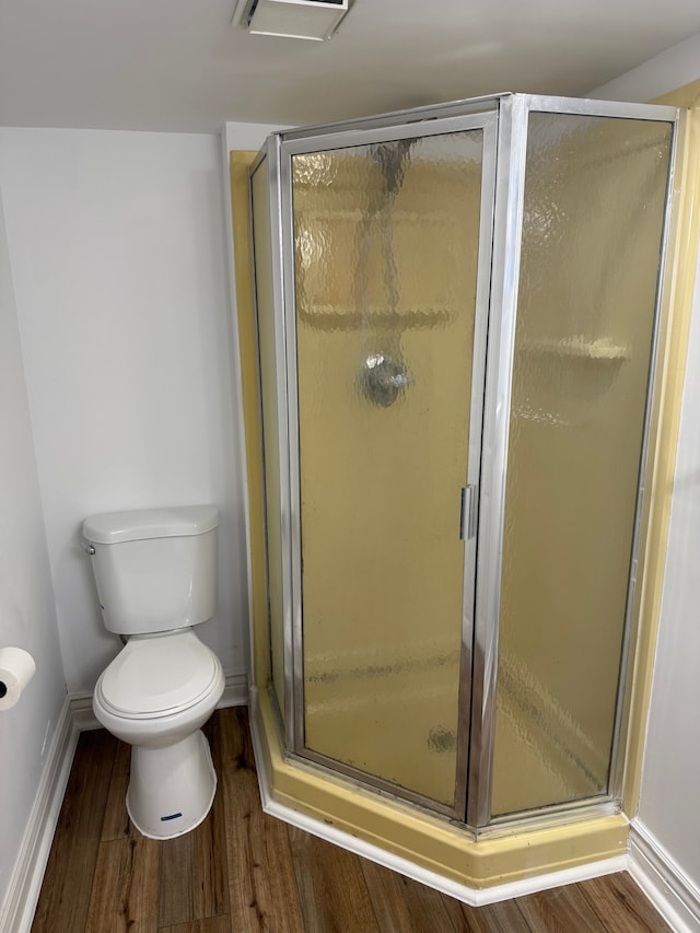 bathroom featuring a stall shower, visible vents, toilet, and wood finished floors