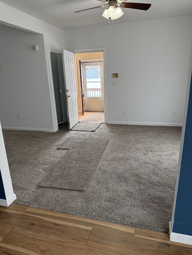 carpeted empty room featuring ceiling fan and baseboards