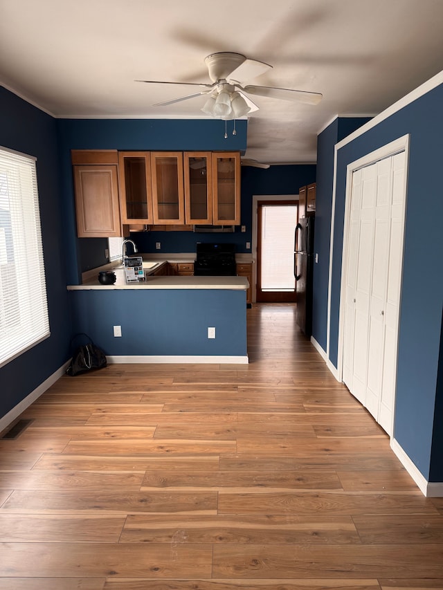 kitchen with black appliances, a peninsula, wood finished floors, and visible vents