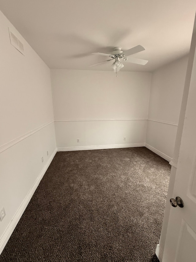 spare room featuring visible vents, dark carpet, a ceiling fan, and baseboards