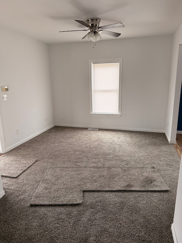 spare room featuring carpet, a ceiling fan, and baseboards