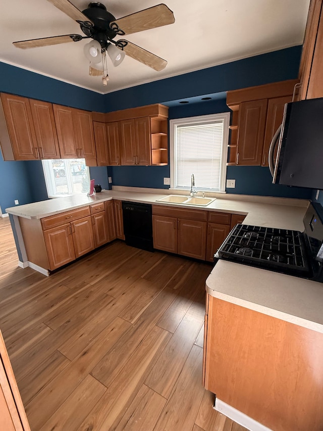 kitchen featuring light wood-style floors, light countertops, black appliances, open shelves, and a sink