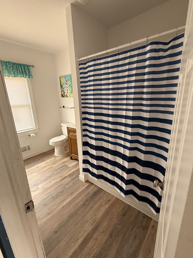 bathroom with visible vents, a shower with shower curtain, toilet, vanity, and wood finished floors