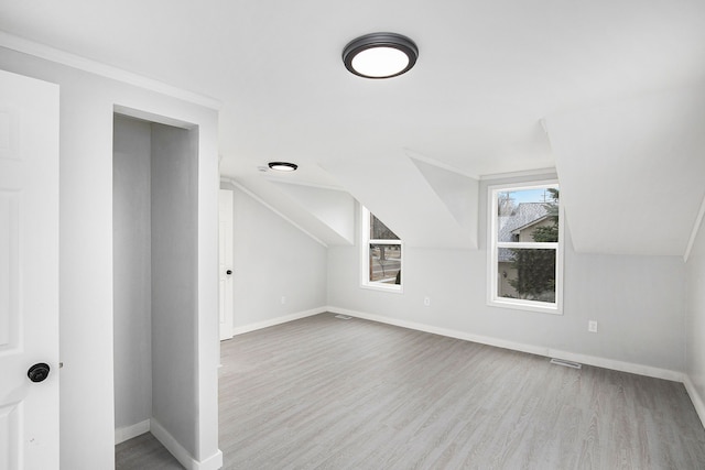 additional living space with light hardwood / wood-style flooring and vaulted ceiling