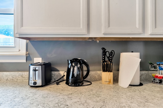 interior details featuring white cabinets and light stone countertops