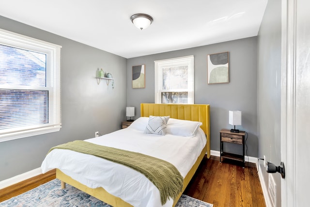 bedroom featuring multiple windows and dark hardwood / wood-style flooring