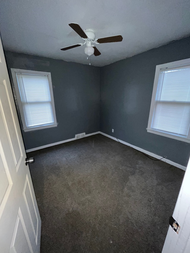 empty room with dark colored carpet and ceiling fan