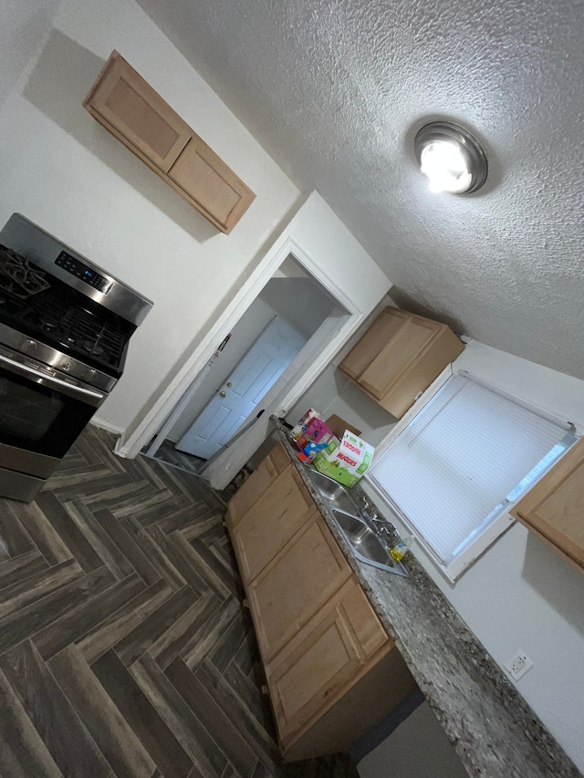 kitchen with dark parquet flooring, light brown cabinetry, and a textured ceiling