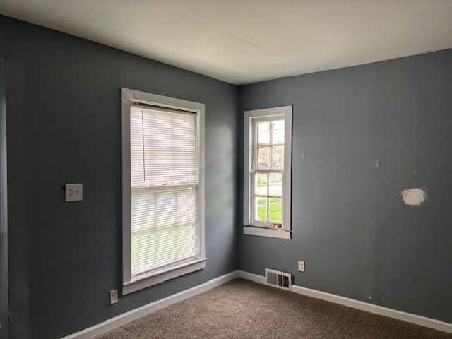 spare room featuring carpet and baseboards