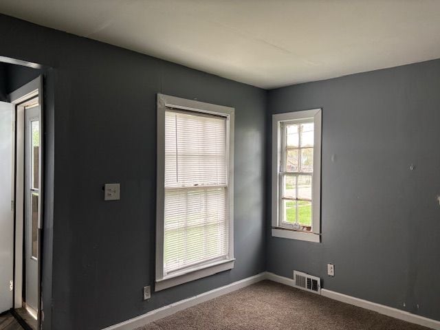 unfurnished room with dark carpet and baseboards