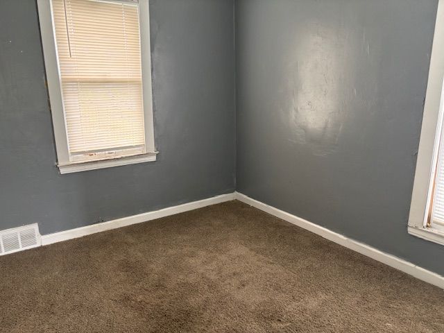 empty room featuring dark colored carpet and baseboards