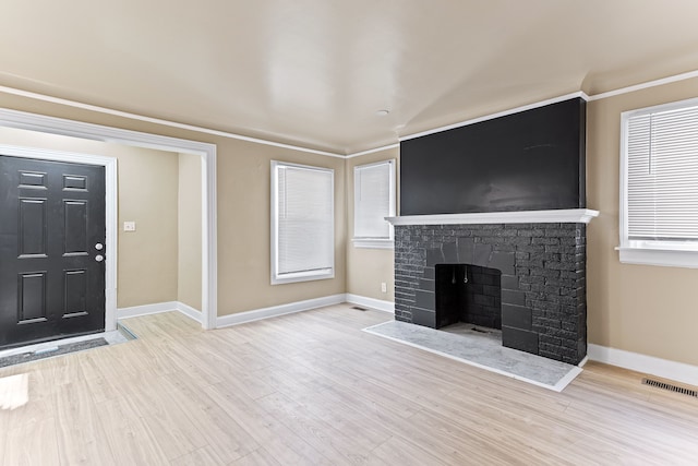 unfurnished living room with a fireplace, light wood-type flooring, and ornamental molding