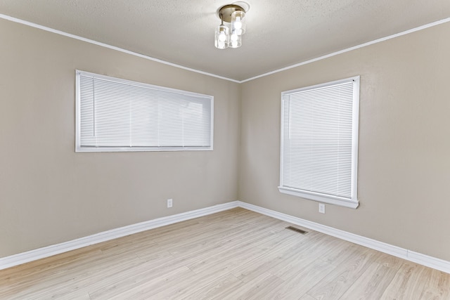 empty room with light hardwood / wood-style floors, a textured ceiling, and ornamental molding