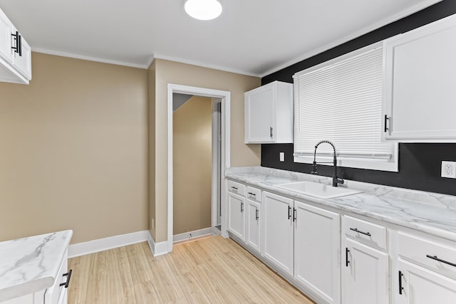 kitchen with light stone countertops, white cabinetry, sink, ornamental molding, and light wood-type flooring