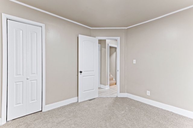 unfurnished bedroom featuring light colored carpet, a closet, and crown molding