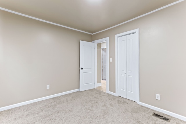 unfurnished bedroom with light colored carpet, a closet, and ornamental molding