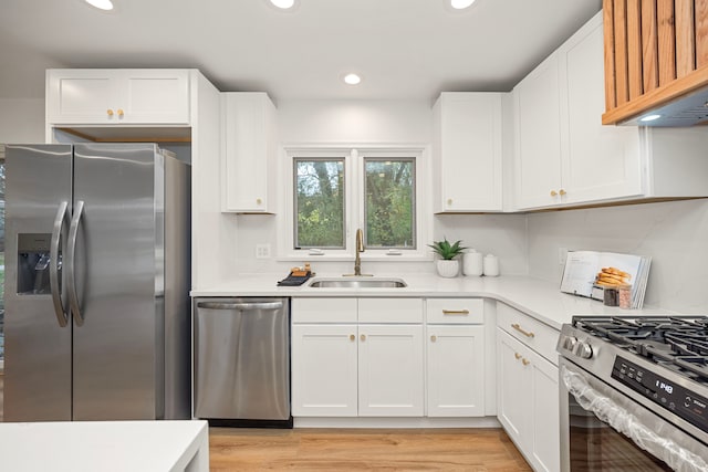 kitchen with sink, light wood-type flooring, white cabinetry, and appliances with stainless steel finishes