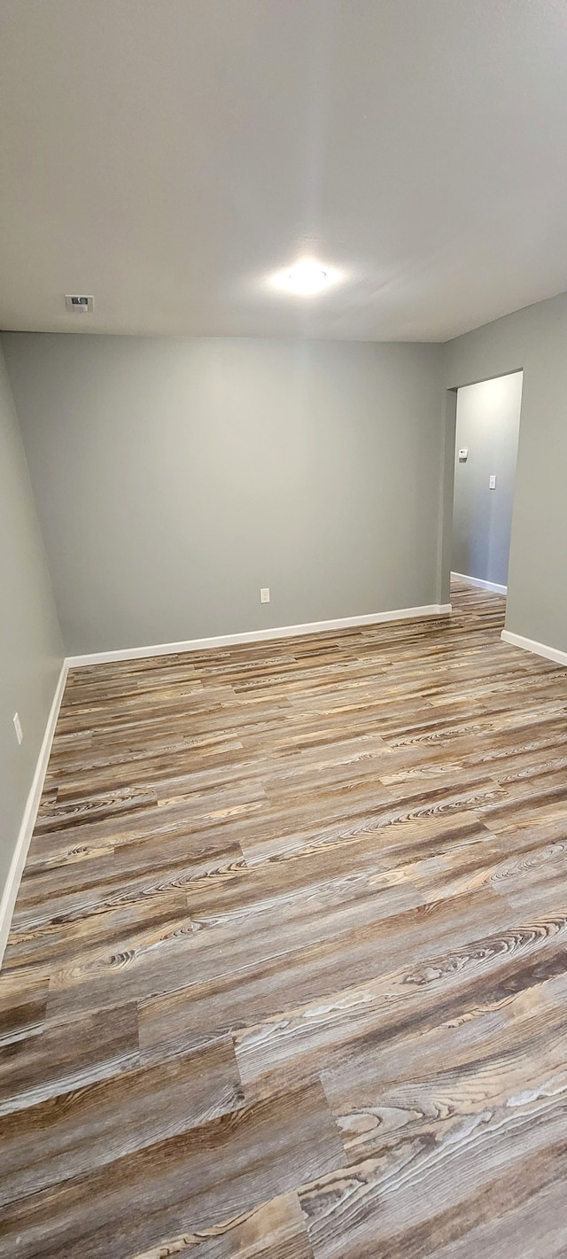 empty room featuring visible vents, baseboards, and wood finished floors