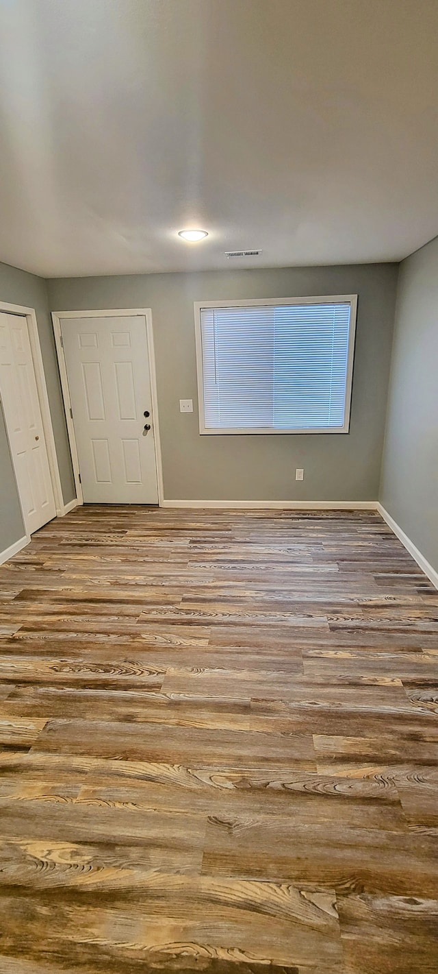 spare room with visible vents, baseboards, and wood finished floors