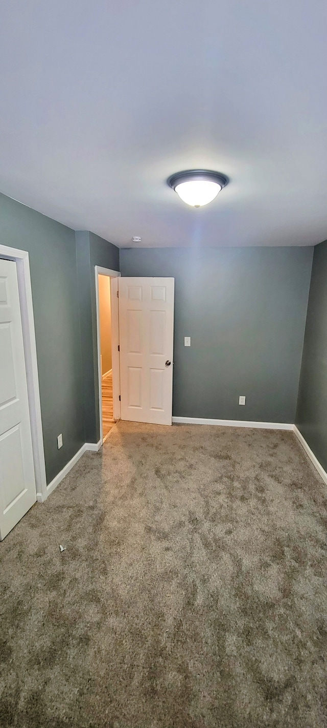 carpeted spare room featuring baseboards