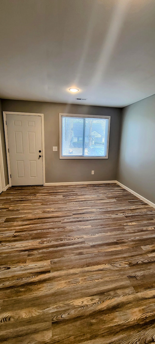 unfurnished room with dark wood finished floors and baseboards