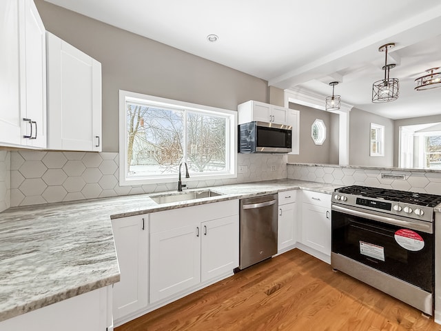 kitchen featuring white cabinets, appliances with stainless steel finishes, decorative backsplash, sink, and light wood-type flooring