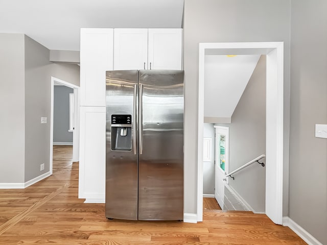 kitchen featuring light wood-type flooring, white cabinetry, stainless steel refrigerator with ice dispenser, and baseboards