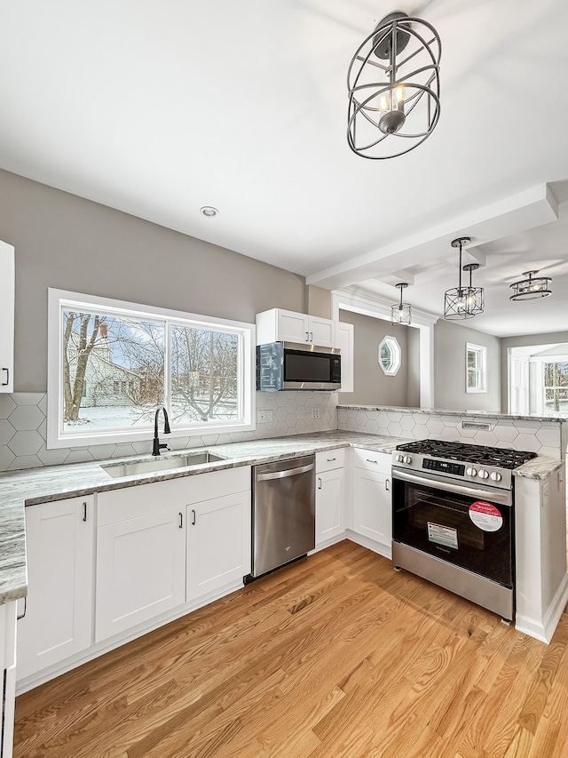 kitchen featuring light wood-style floors, appliances with stainless steel finishes, backsplash, and a sink