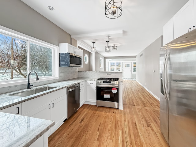 kitchen featuring appliances with stainless steel finishes, tasteful backsplash, white cabinetry, sink, and pendant lighting