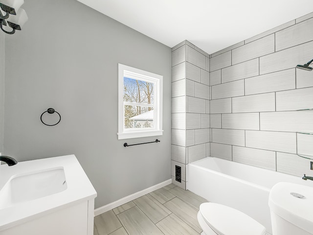 bathroom featuring toilet, bathing tub / shower combination, baseboards, and vanity