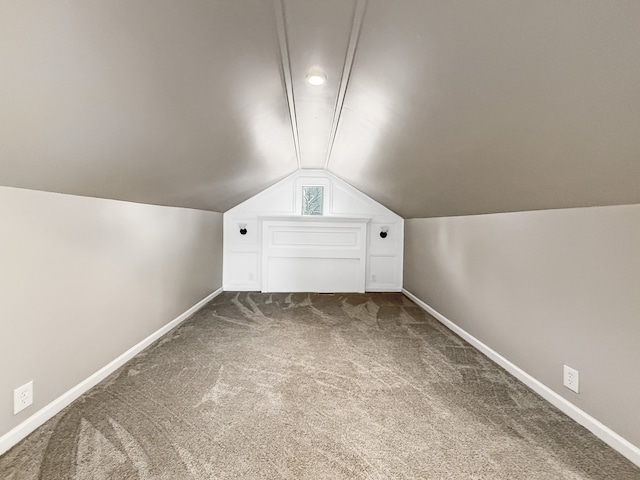 bonus room featuring dark colored carpet, lofted ceiling, and baseboards