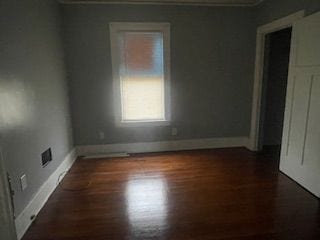 unfurnished room with dark wood-type flooring