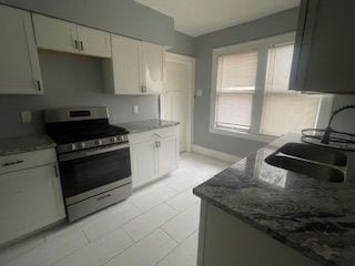 kitchen featuring white cabinetry, sink, electric range, and dark stone counters