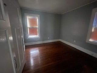 unfurnished room featuring crown molding and dark wood-type flooring