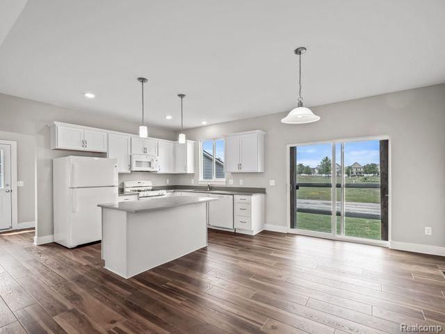 kitchen featuring decorative light fixtures, white appliances, white cabinetry, and a kitchen island